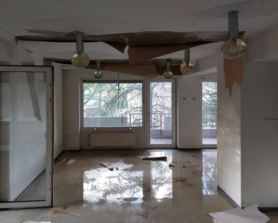 Apartment living room with a collapsed ceiling and water across the floor