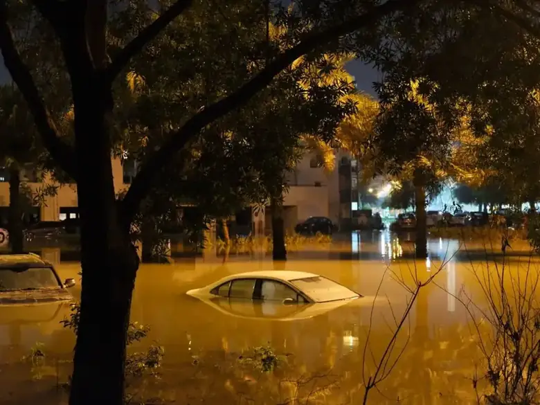 Night flood water covering a street and a parked car after heavy rain
