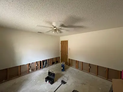 Bedroom with drywall cut away at the base so the wall cavities can dry